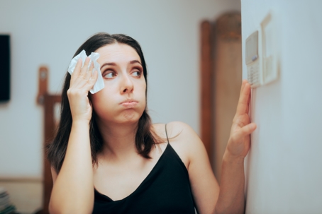 Woman Feeling Hot During Summer Setting Her Thermostat