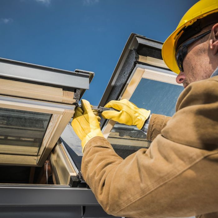 A worker using a screwdriver on the windows of a building